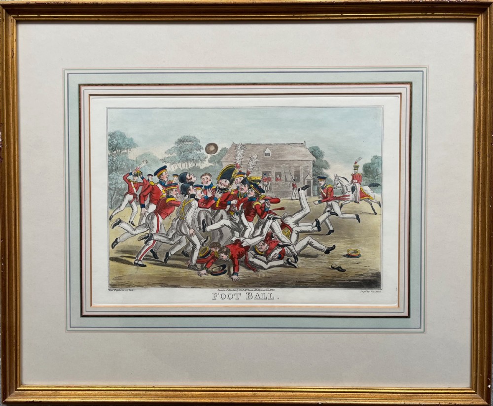 A framed Georgian hand-coloured engraving depicting men in military attire playing football, set within a lined mount and a gilded wooden frame.
