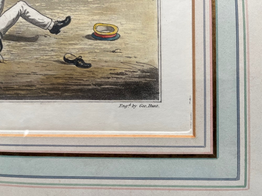 A framed Georgian hand-coloured engraving depicting men in military attire playing football, set within a lined mount and a gilded wooden frame. View IV