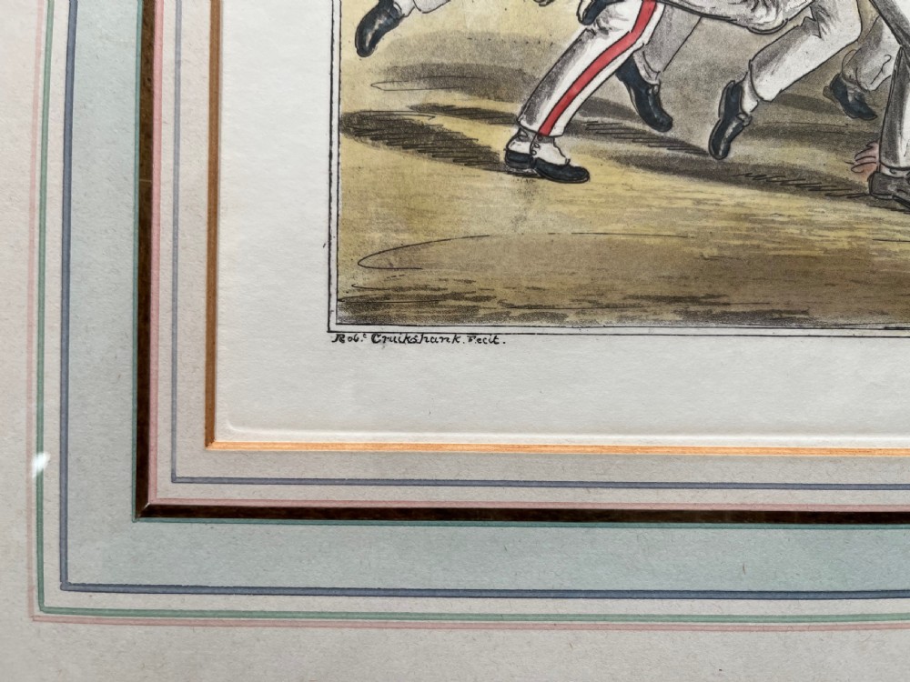 A framed Georgian hand-coloured engraving depicting men in military attire playing football, set within a lined mount and a gilded wooden frame. View V