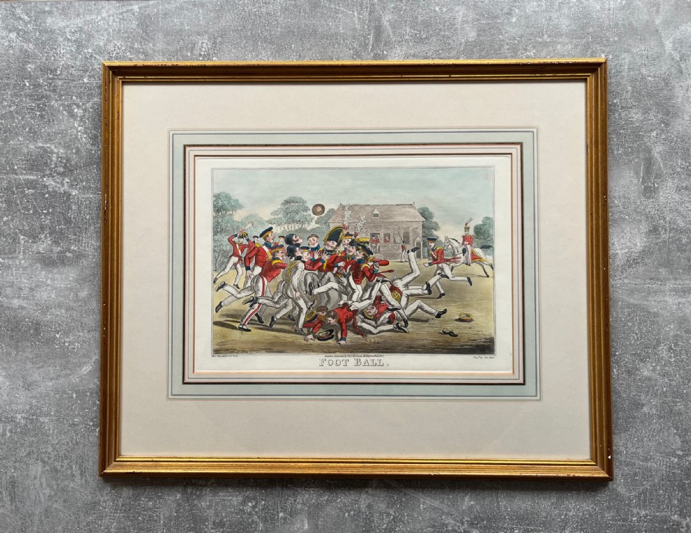 A framed Georgian hand-coloured engraving depicting men in military attire playing football, set within a lined mount and a gilded wooden frame. View VI