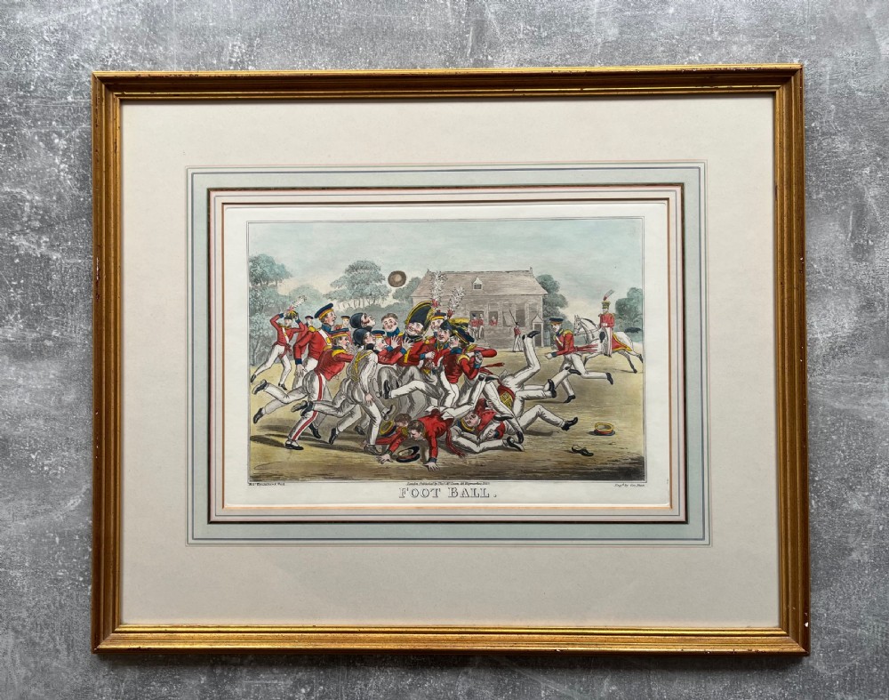 A framed Georgian hand-coloured engraving depicting men in military attire playing football, set within a lined mount and a gilded wooden frame. View VII