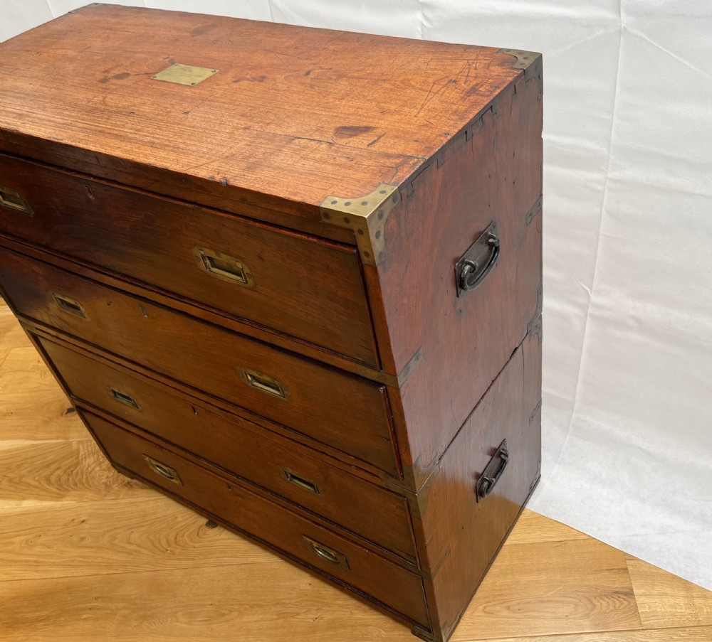 A teak campaign secretaire chest featuring brass corner brackets, flush brass drawer handles, and an open fall-front writing surface lined with green felt. View II