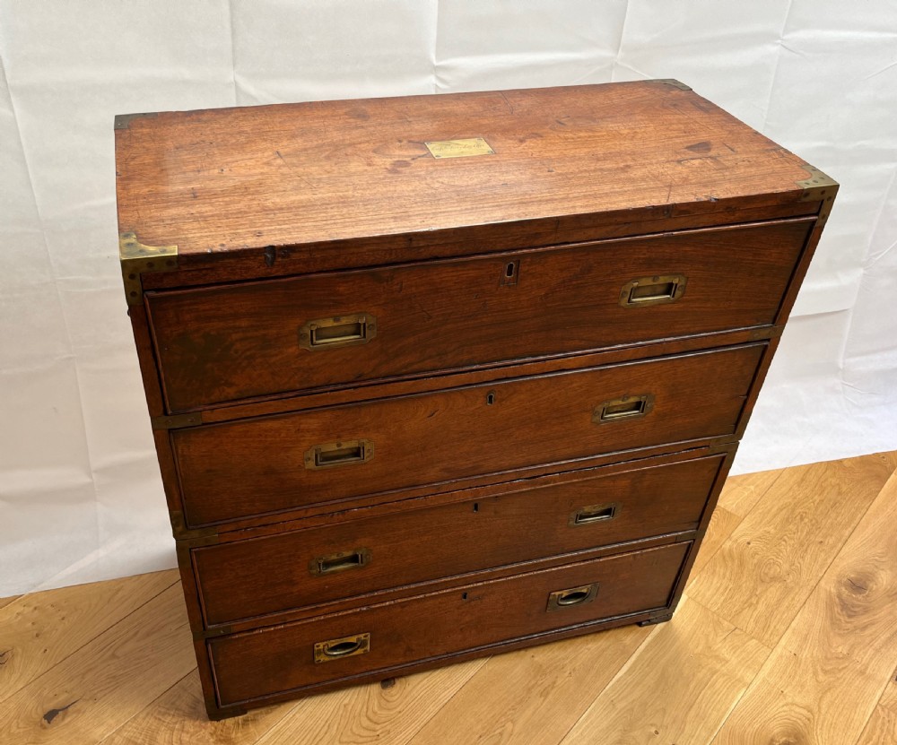 A teak campaign secretaire chest featuring brass corner brackets, flush brass drawer handles, and an open fall-front writing surface lined with green felt. View III