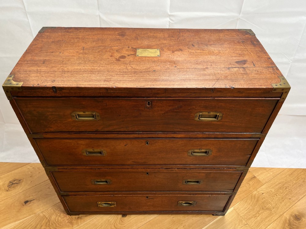 A teak campaign secretaire chest featuring brass corner brackets, flush brass drawer handles, and an open fall-front writing surface lined with green felt. View VII