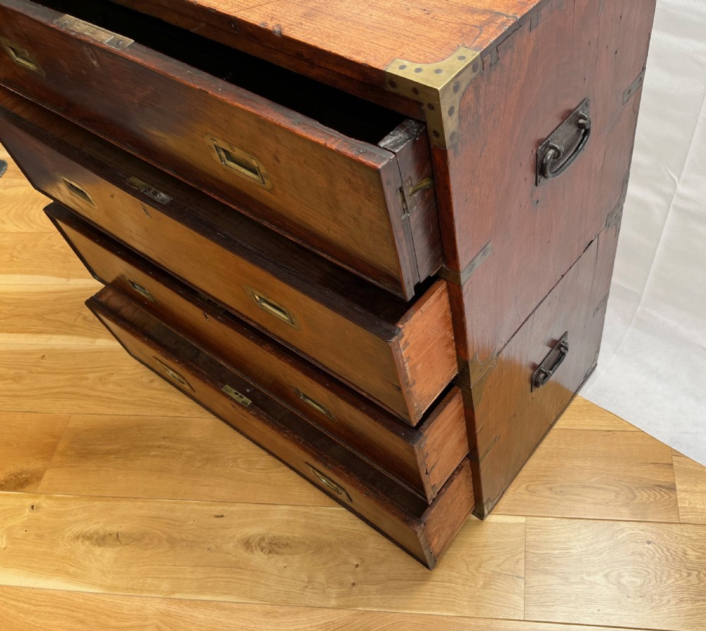 A teak campaign secretaire chest featuring brass corner brackets, flush brass drawer handles, and an open fall-front writing surface lined with green felt. View X