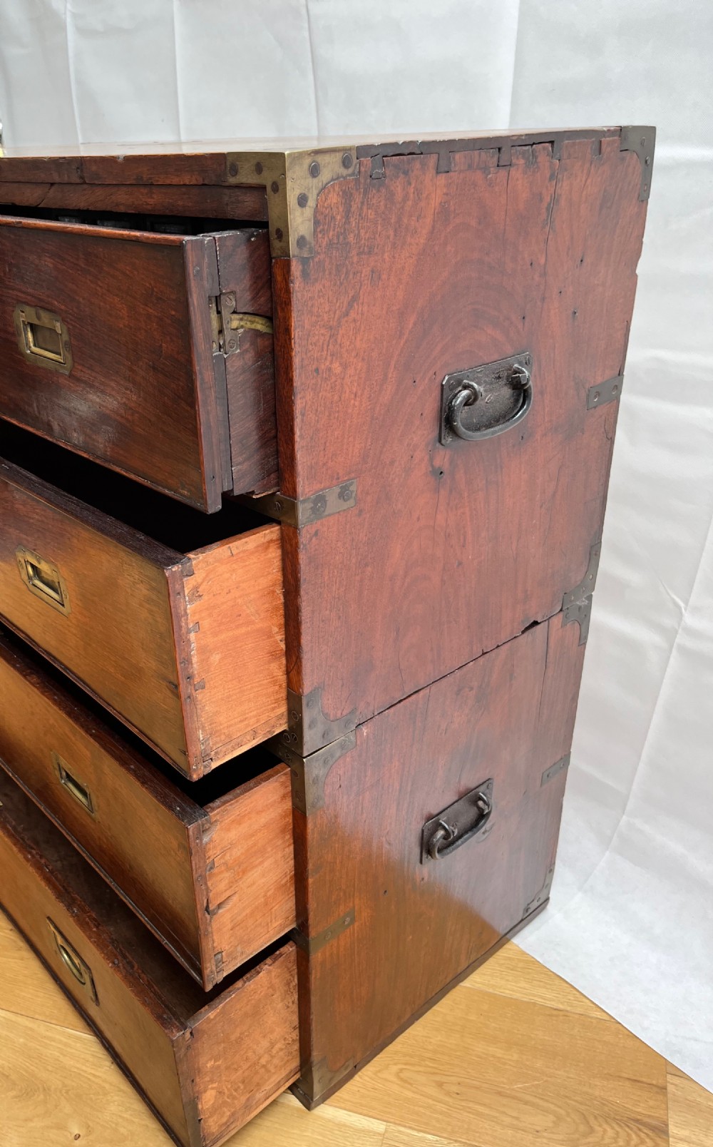 A teak campaign secretaire chest featuring brass corner brackets, flush brass drawer handles, and an open fall-front writing surface lined with green felt. View XI