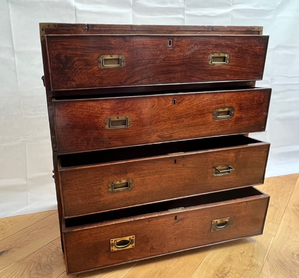 A teak campaign secretaire chest featuring brass corner brackets, flush brass drawer handles, and an open fall-front writing surface lined with green felt. View XII