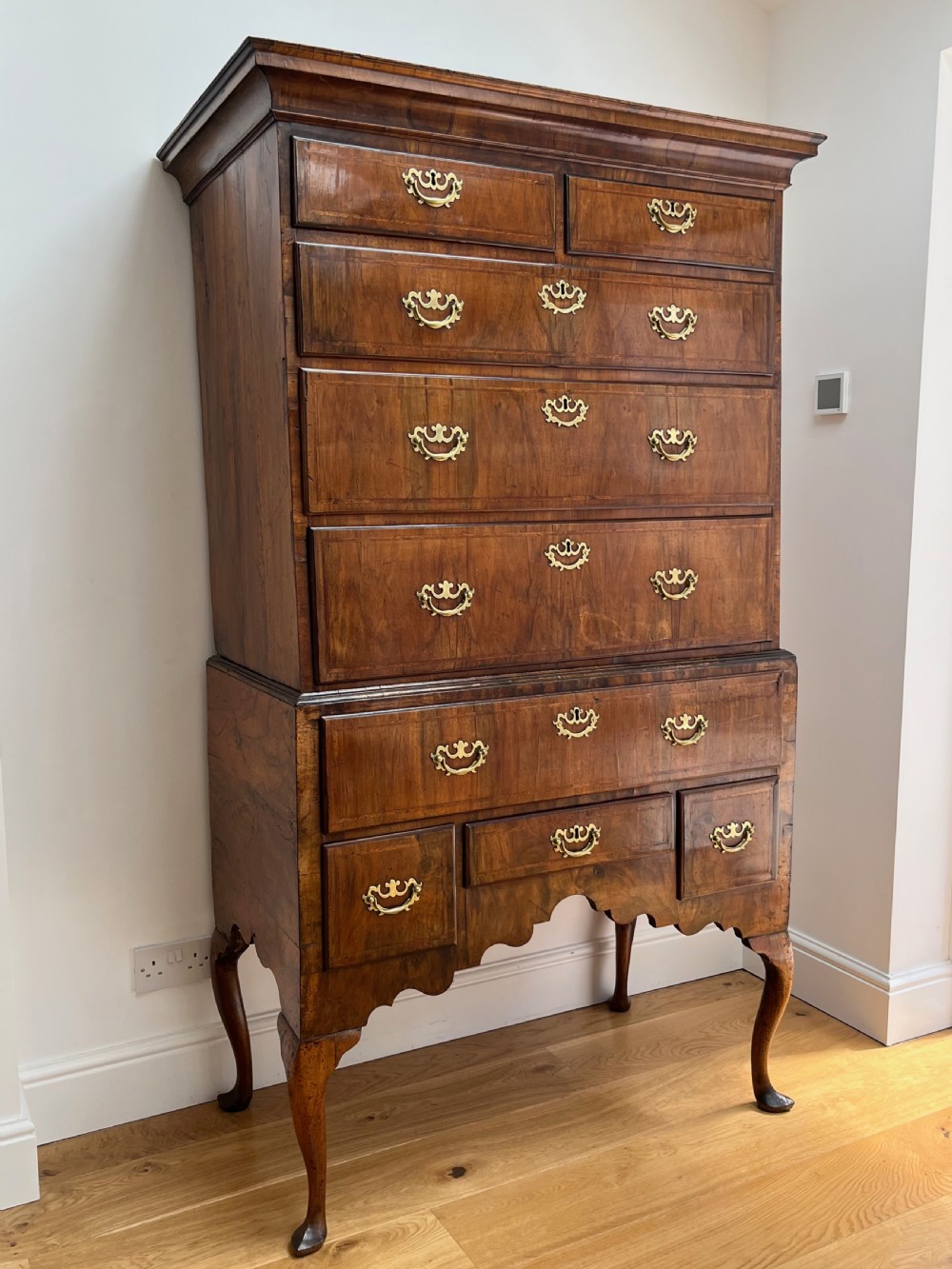 An early 18th-century walnut chest on stand featuring graduated drawers, decorative brass handles, a shaped apron, and four cabriole legs. View III