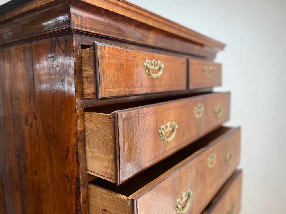 An early 18th-century walnut chest on stand featuring graduated drawers, decorative brass handles, a shaped apron, and four cabriole legs. View VIII