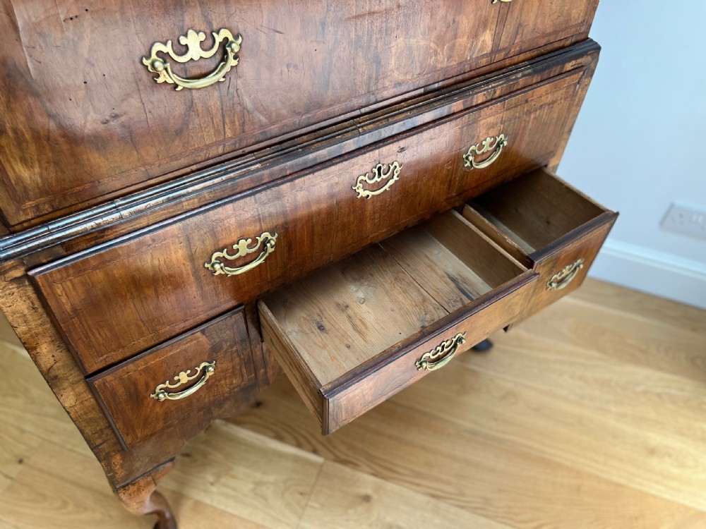 An early 18th-century walnut chest on stand featuring graduated drawers, decorative brass handles, a shaped apron, and four cabriole legs. View XI