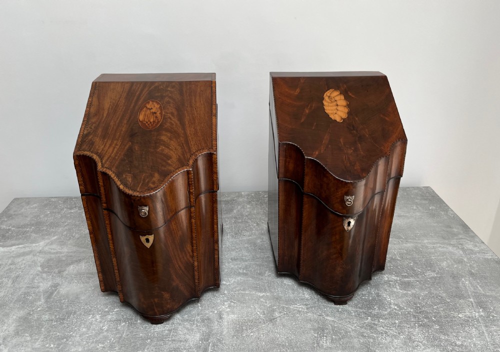 A matched pair of George III flame mahogany knife boxes featuring sloped lids with shell marquetry inlays and serpentine fronts.