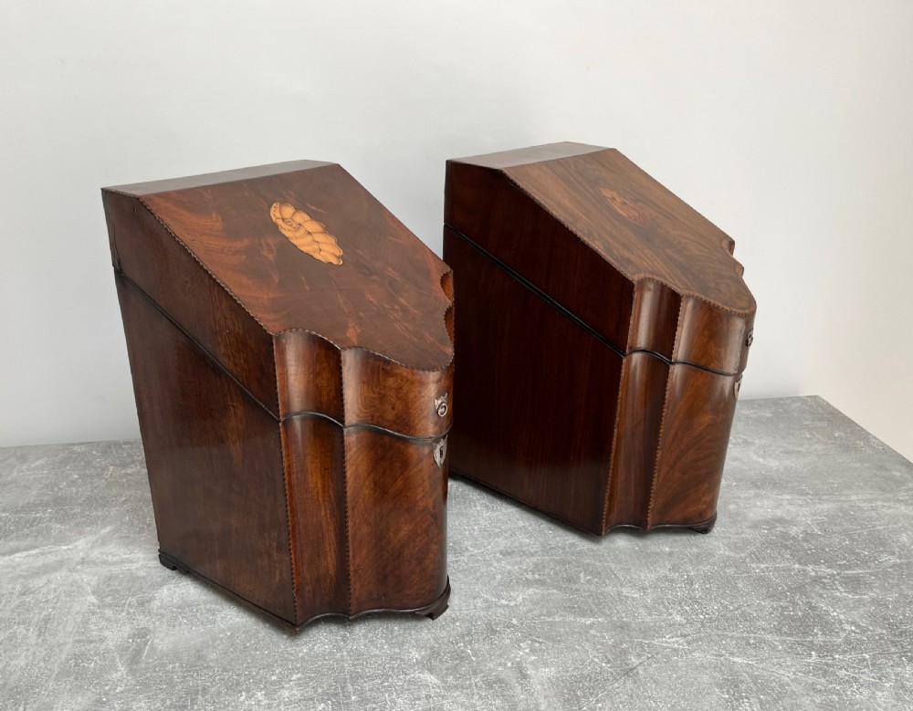 A matched pair of George III flame mahogany knife boxes featuring sloped lids with shell marquetry inlays and serpentine fronts. View III
