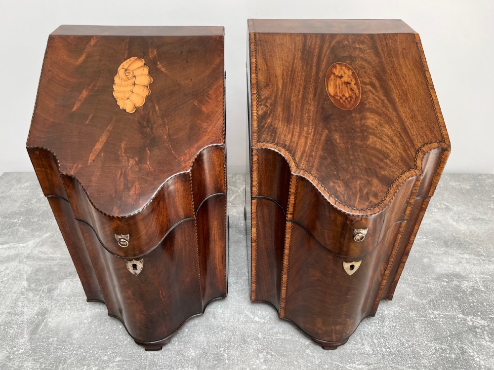 A matched pair of George III flame mahogany knife boxes featuring sloped lids with shell marquetry inlays and serpentine fronts. View IV