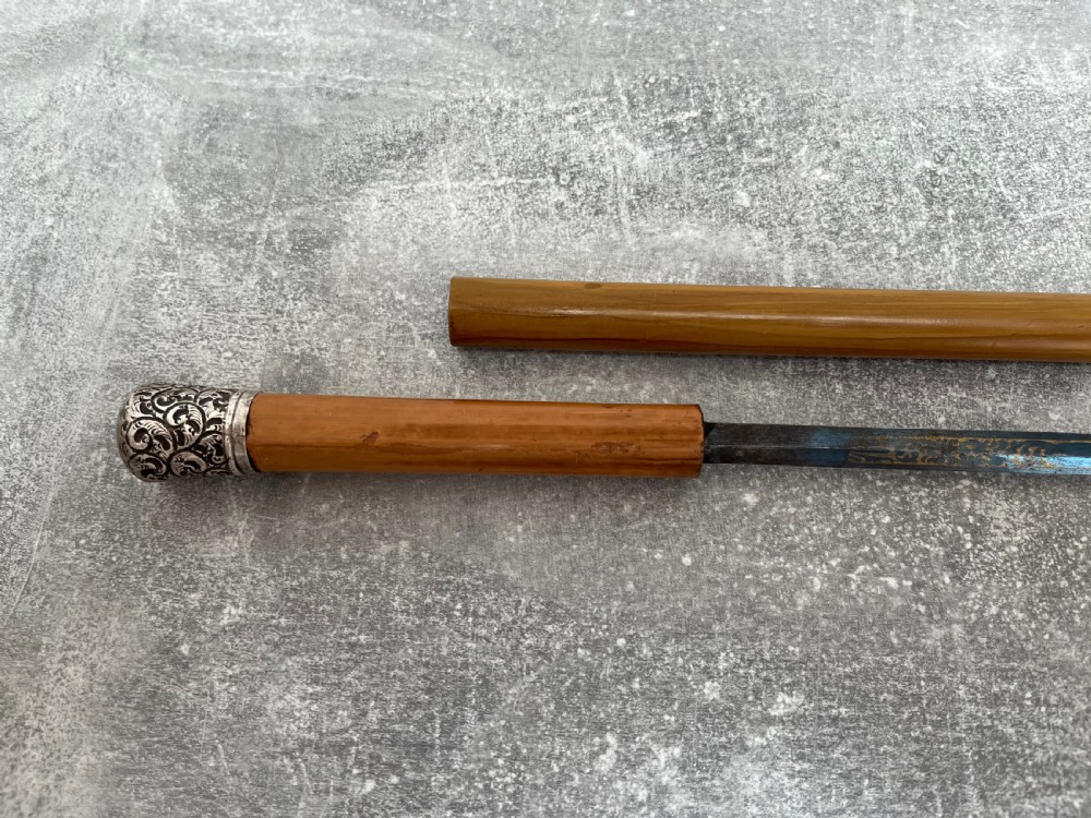 A late Victorian Malacca cane sword stick featuring a silver repousse embossed knop handle and a concealed steel blade alongside its wooden sheath. View III