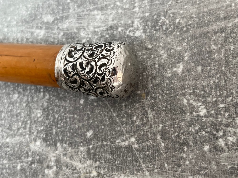 A late Victorian Malacca cane sword stick featuring a silver repousse embossed knop handle and a concealed steel blade alongside its wooden sheath. View IV