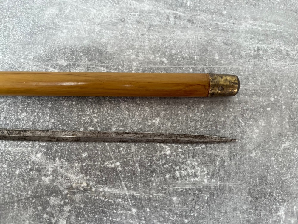 A late Victorian Malacca cane sword stick featuring a silver repousse embossed knop handle and a concealed steel blade alongside its wooden sheath. View IX