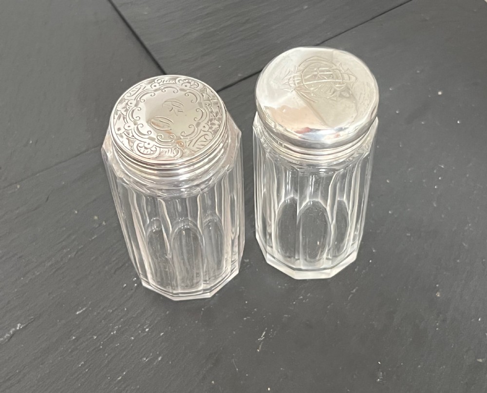 Pair of faceted clear cut glass vanity jars fitted with silver tops featuring engraved and chased detailing.