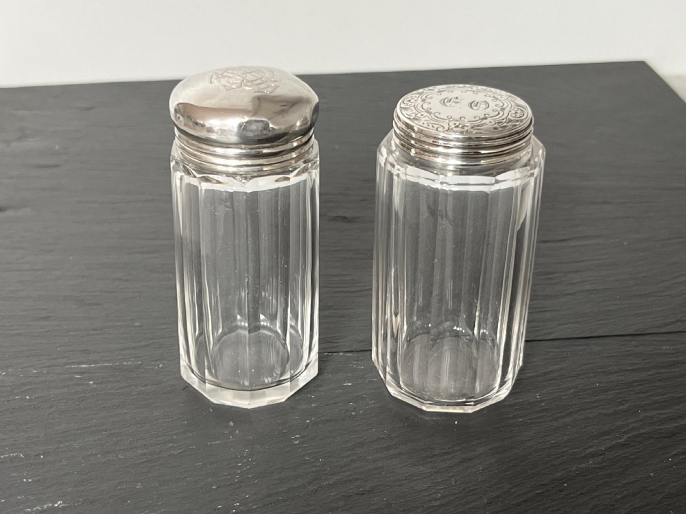 Pair of faceted clear cut glass vanity jars fitted with silver tops featuring engraved and chased detailing. View II
