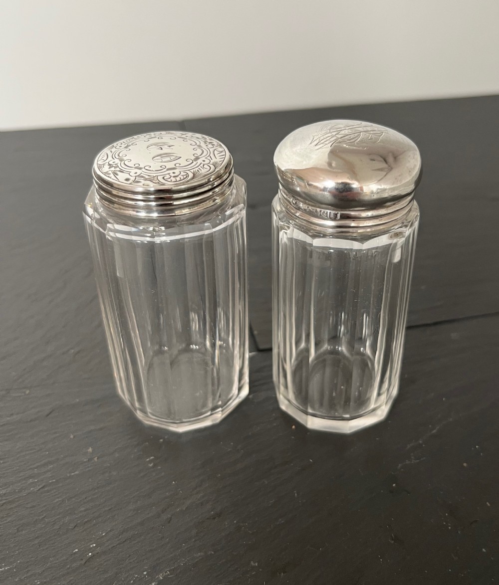 Pair of faceted clear cut glass vanity jars fitted with silver tops featuring engraved and chased detailing. View VIII