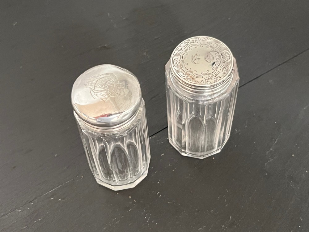 Pair of faceted clear cut glass vanity jars fitted with silver tops featuring engraved and chased detailing. View X