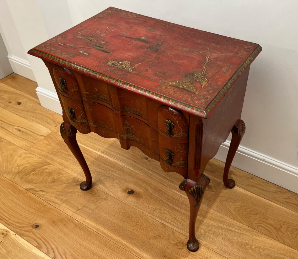 A red lacquered side table decorated with hand-painted gilt chinoiserie landscapes, featuring two drawers with brass handles and long cabriole legs. View II