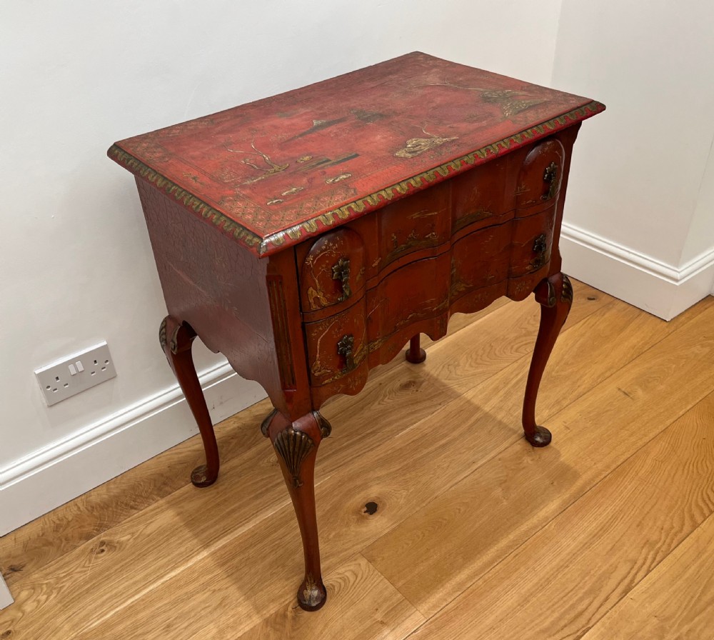 A red lacquered side table decorated with hand-painted gilt chinoiserie landscapes, featuring two drawers with brass handles and long cabriole legs. View III