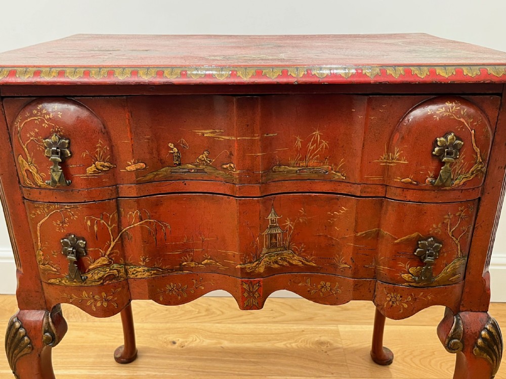 A red lacquered side table decorated with hand-painted gilt chinoiserie landscapes, featuring two drawers with brass handles and long cabriole legs. View IV