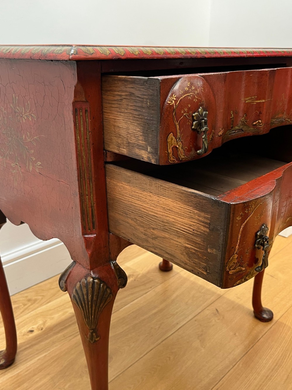 A red lacquered side table decorated with hand-painted gilt chinoiserie landscapes, featuring two drawers with brass handles and long cabriole legs. View XIII