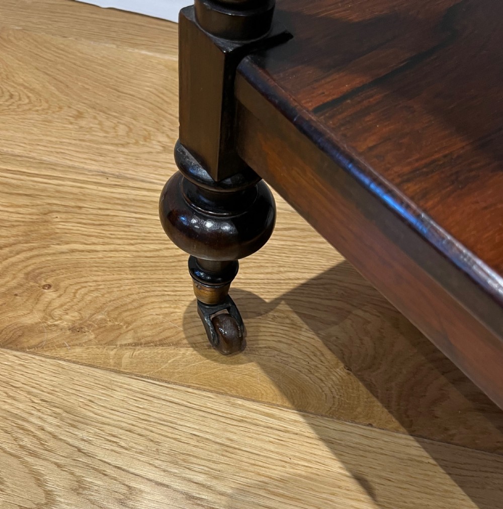 A mid-Victorian dark rosewood whatnot etagere featuring three open tiers, barley twist pillar supports, a central drawer, a gallery back, and turned feet. View VIII
