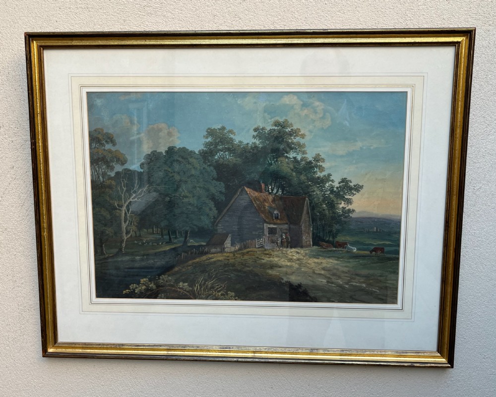 A framed 19th-century watercolour painting featuring a rustic cottage nestled among lush trees with livestock in a rolling landscape, presented in a gilt frame. View VI