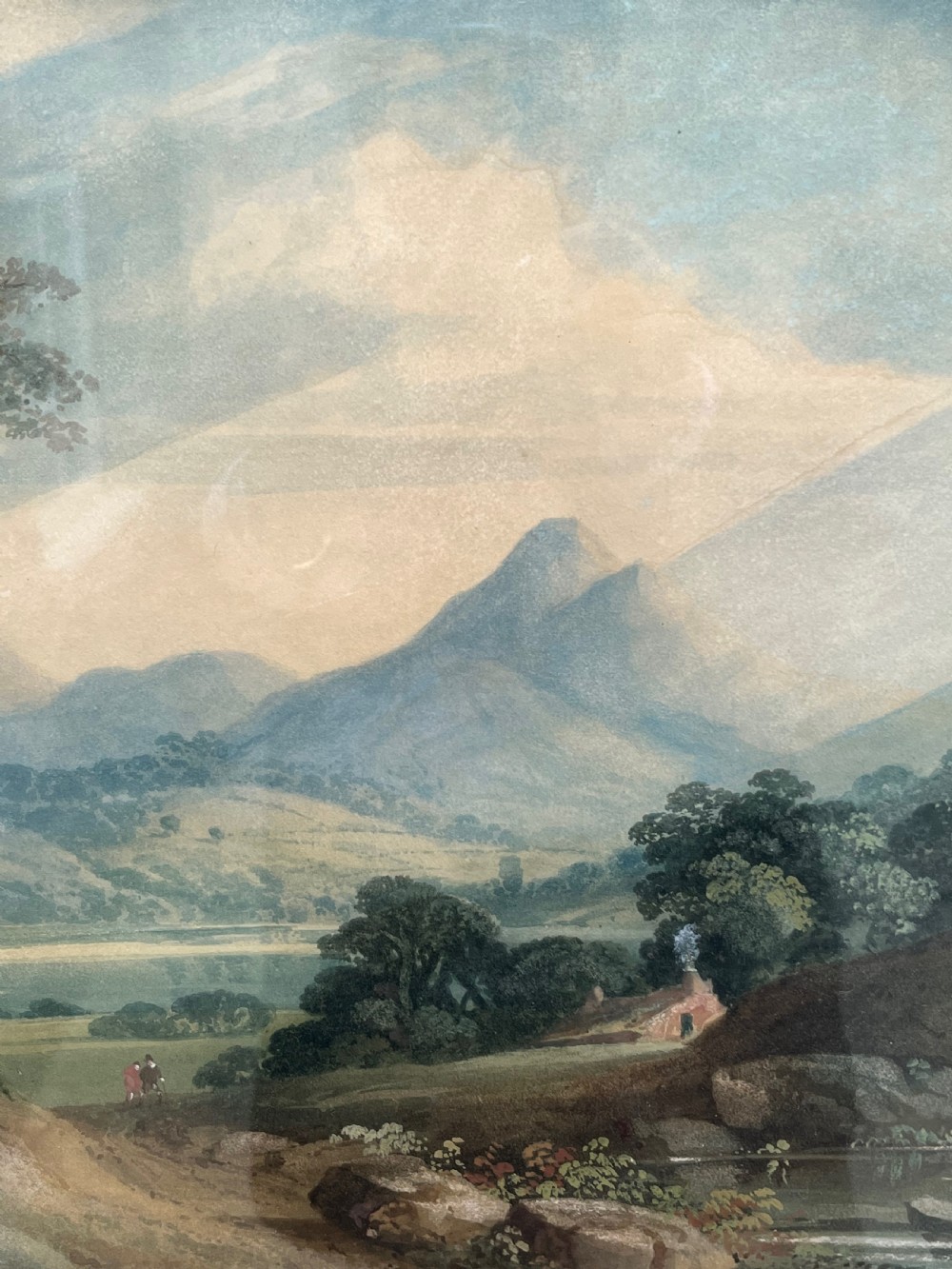 A framed 19th-century watercolour painting featuring a rustic cottage nestled among lush trees with livestock in a rolling landscape, presented in a gilt frame. View XI