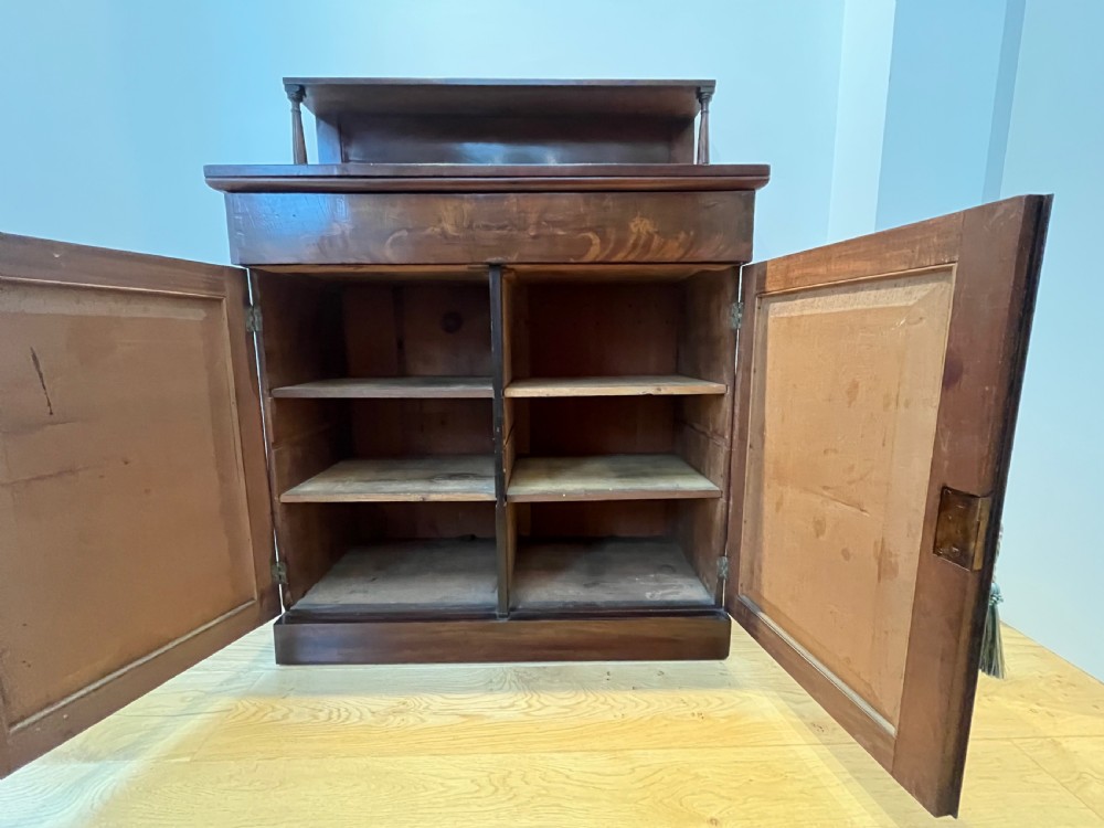 A Regency flame mahogany chiffonier cabinet featuring a top display shelf supported by turned columns over a frieze drawer and two panelled doors. View VII