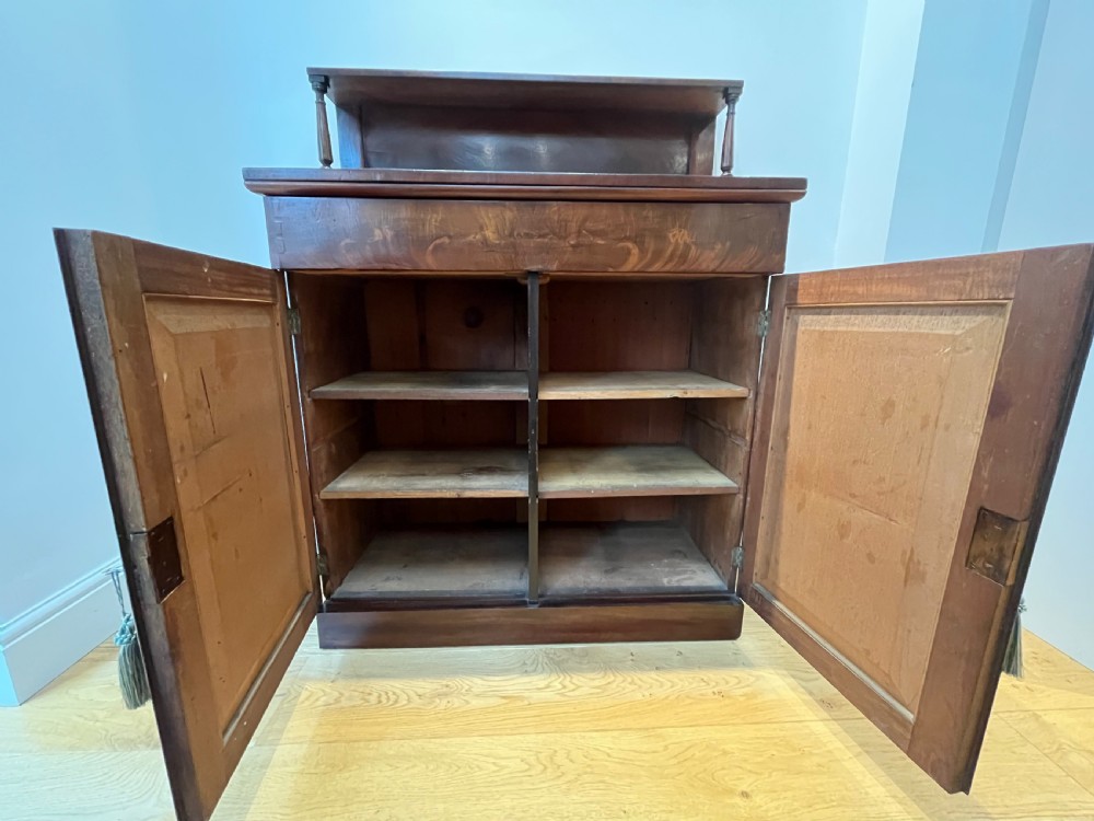 A Regency flame mahogany chiffonier cabinet featuring a top display shelf supported by turned columns over a frieze drawer and two panelled doors. View VIII