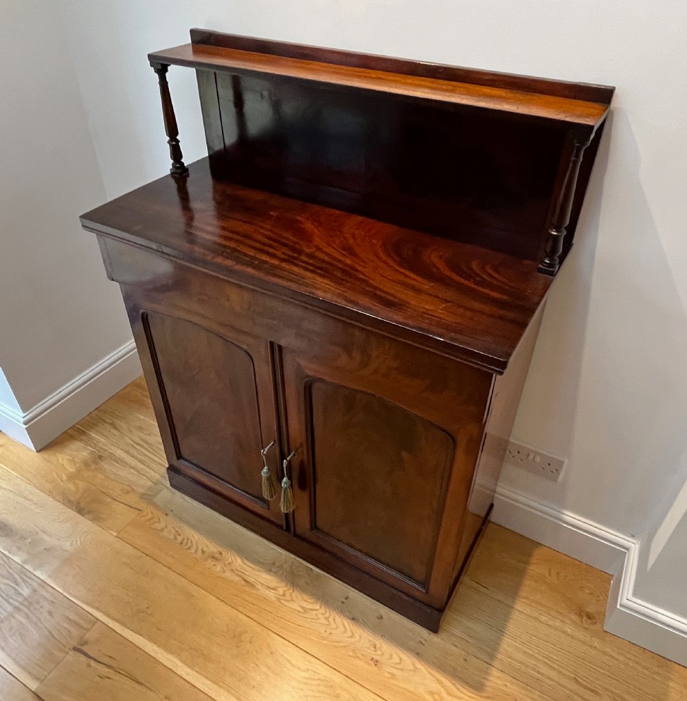 A Regency flame mahogany chiffonier cabinet featuring a top display shelf supported by turned columns over a frieze drawer and two panelled doors. View XII