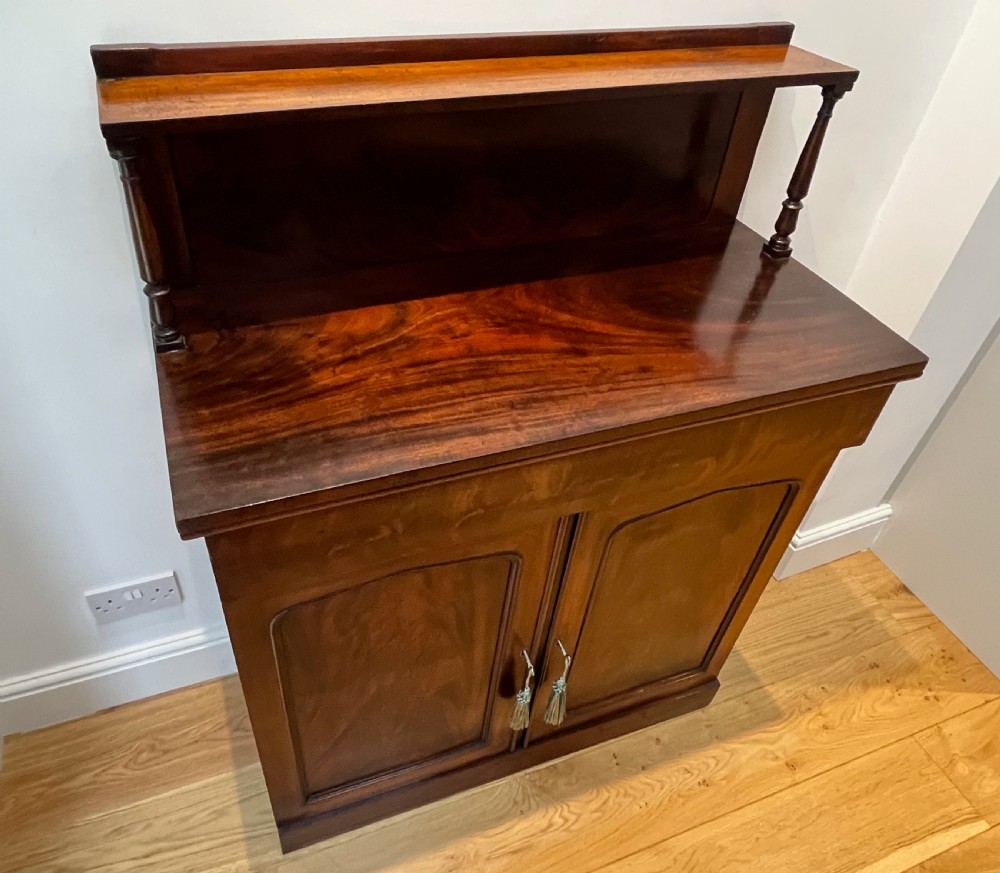 A Regency flame mahogany chiffonier cabinet featuring a top display shelf supported by turned columns over a frieze drawer and two panelled doors. View XIII