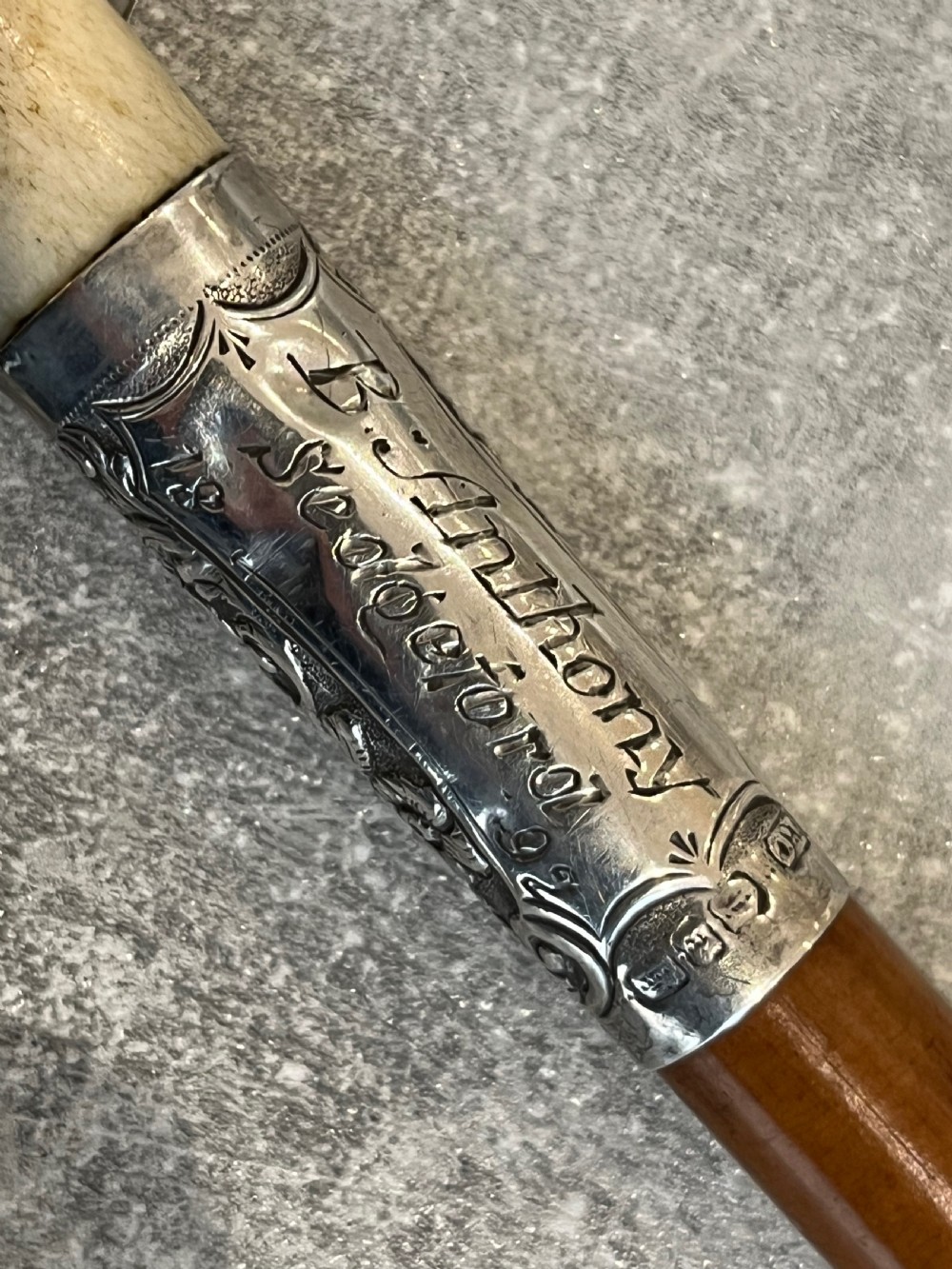 Close-up of a silver-mounted riding crop featuring a carved antler handle, a chased sterling silver collar, and a polished wooden shaft. View III
