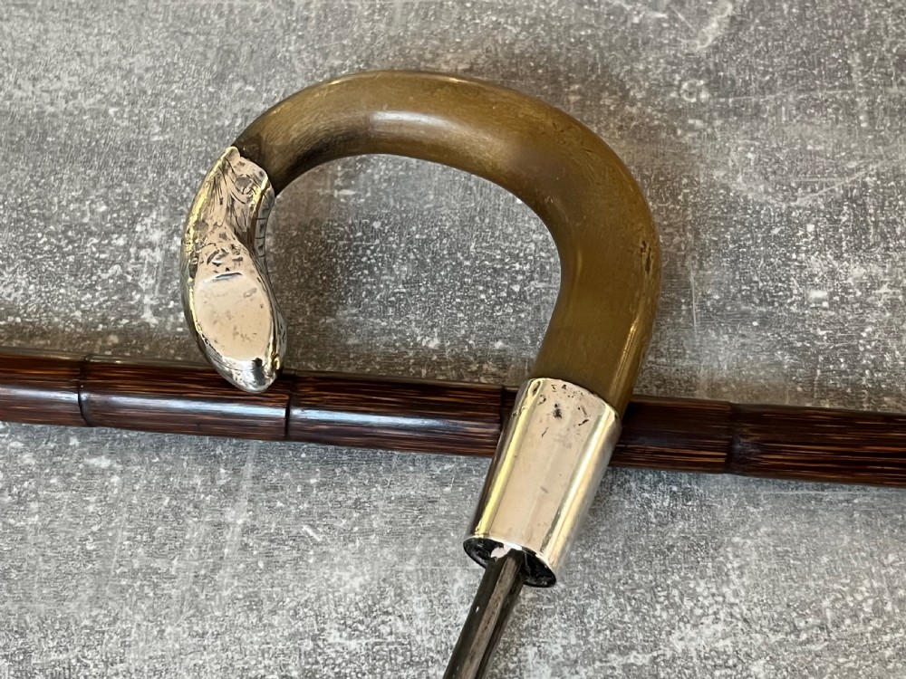 An Edwardian silver-mounted sword stick with a curved crook handle, silver collar bearing London hallmarks, and a partially unsheathed steel blade. View VIII