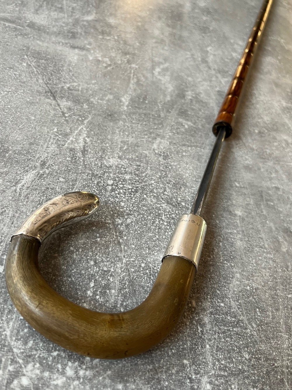 An Edwardian silver-mounted sword stick with a curved crook handle, silver collar bearing London hallmarks, and a partially unsheathed steel blade. View IX