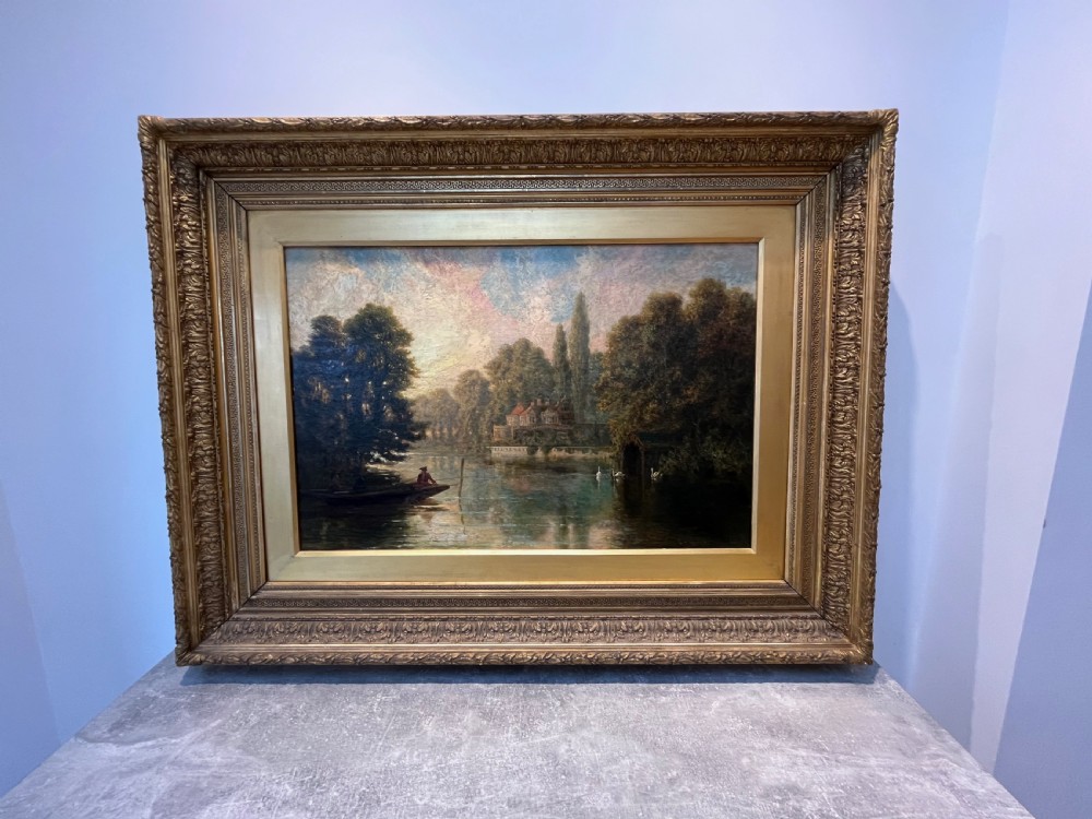 An antique framed oil painting depicting a tranquil river Thames scene with a figure in a boat, swans near a boathouse, and a riverbank estate beneath a glowing sky. View VIII