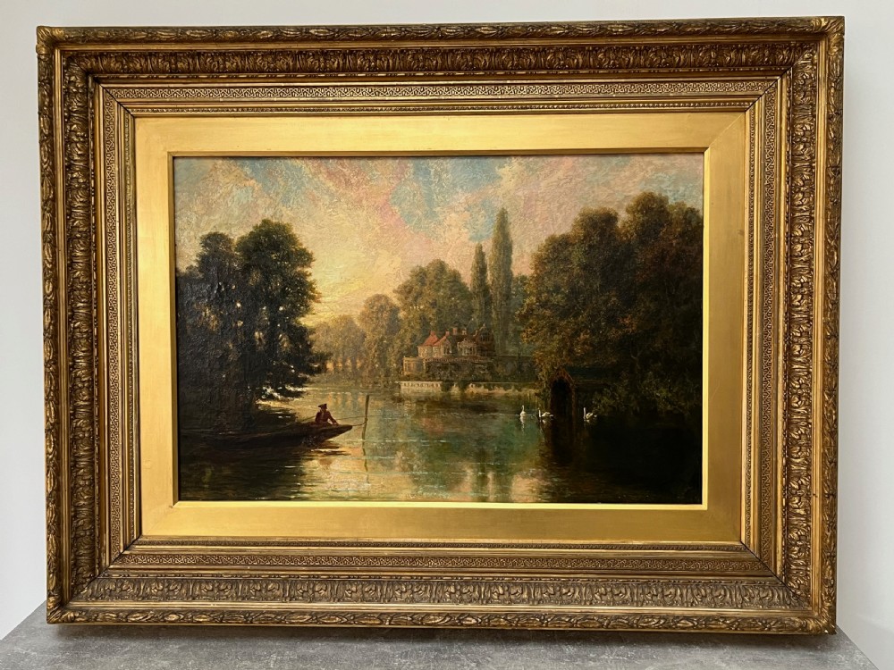 An antique framed oil painting depicting a tranquil river Thames scene with a figure in a boat, swans near a boathouse, and a riverbank estate beneath a glowing sky. View XIII