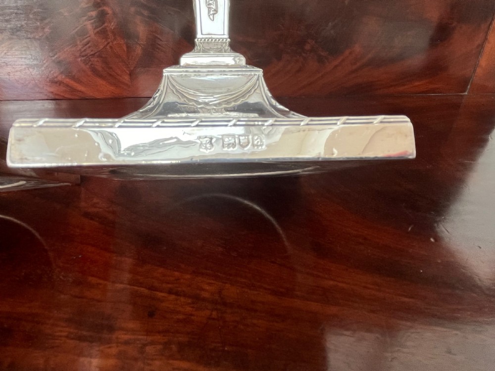 A pair of Victorian sterling silver candlesticks featuring urn-shaped sockets, relief swags on square stepped bases, and tapering columns. View IV