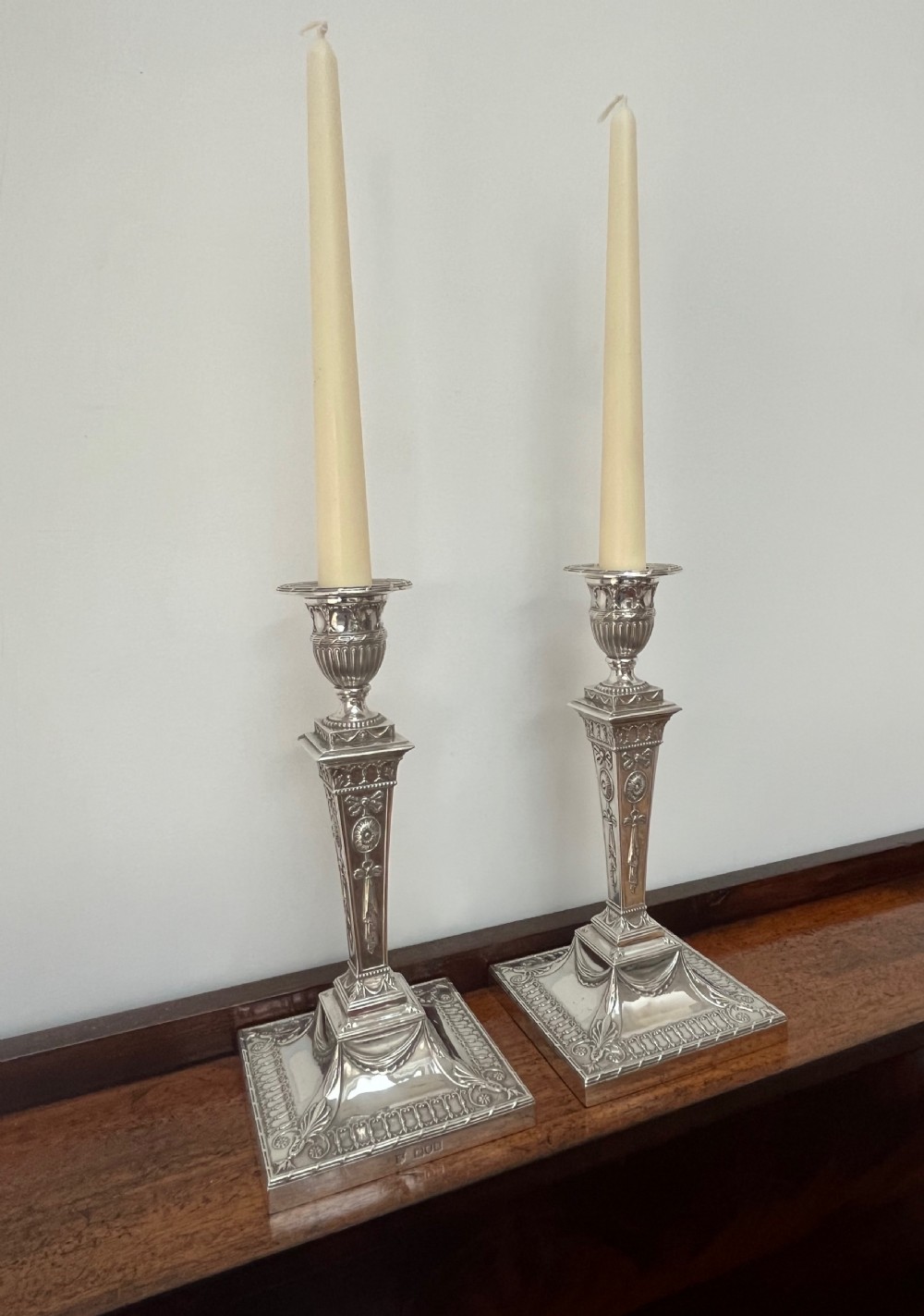 A pair of Victorian sterling silver candlesticks featuring urn-shaped sockets, relief swags on square stepped bases, and tapering columns. View XIII