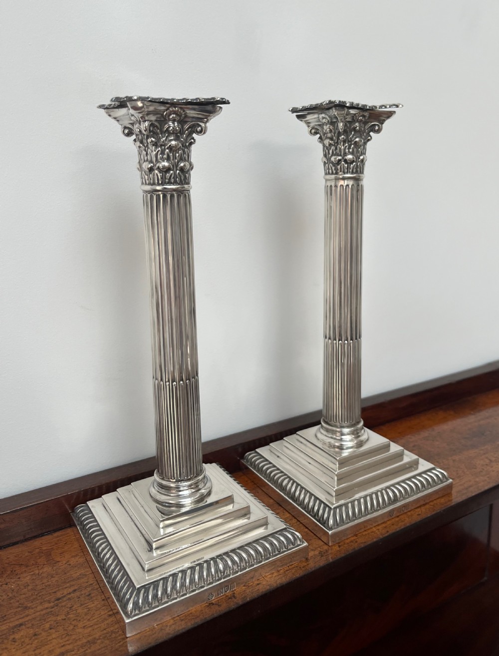 A pair of Edwardian sterling silver Corinthian column candlesticks on stepped square bases with gadrooned rims. View II