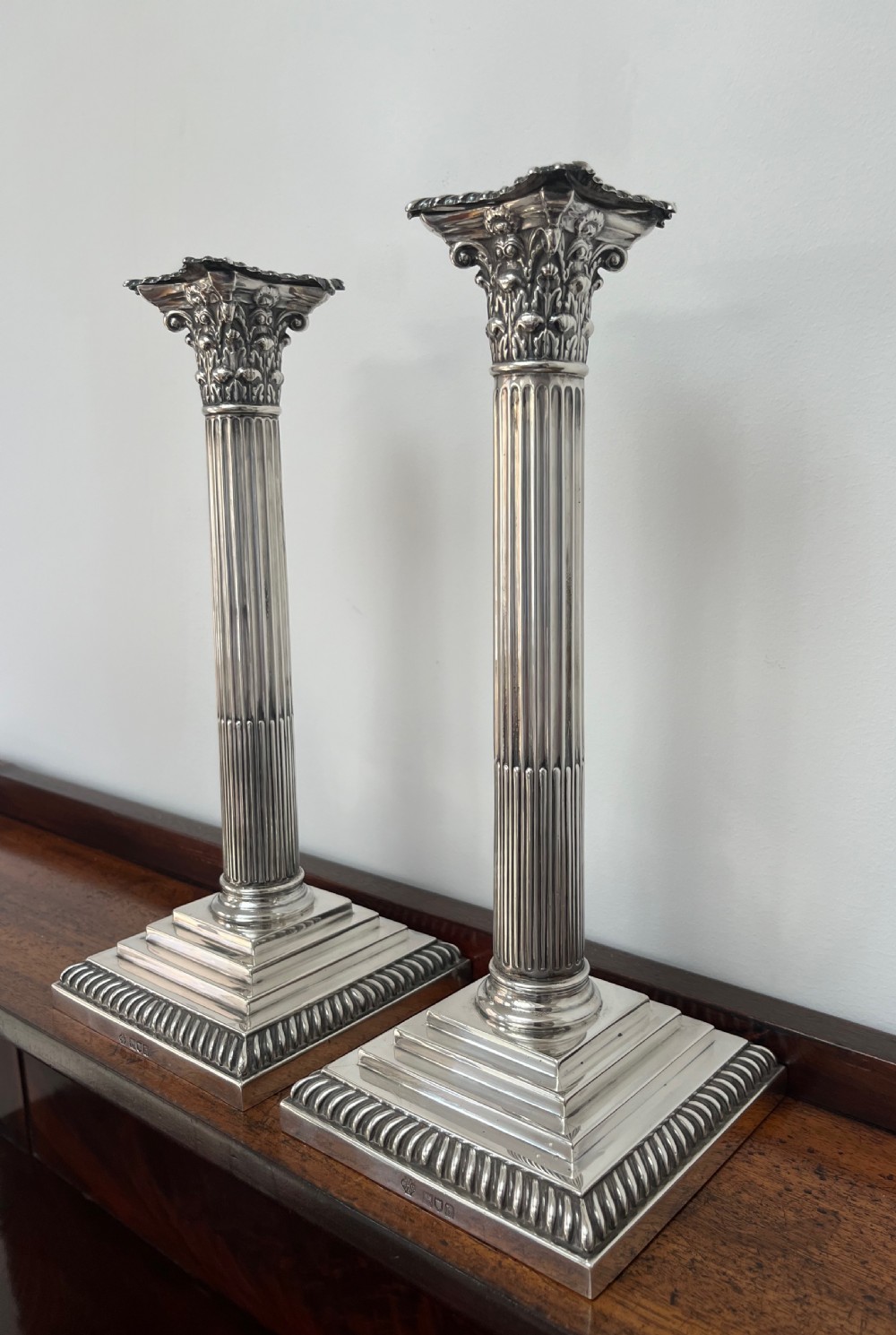 A pair of Edwardian sterling silver Corinthian column candlesticks on stepped square bases with gadrooned rims. View III