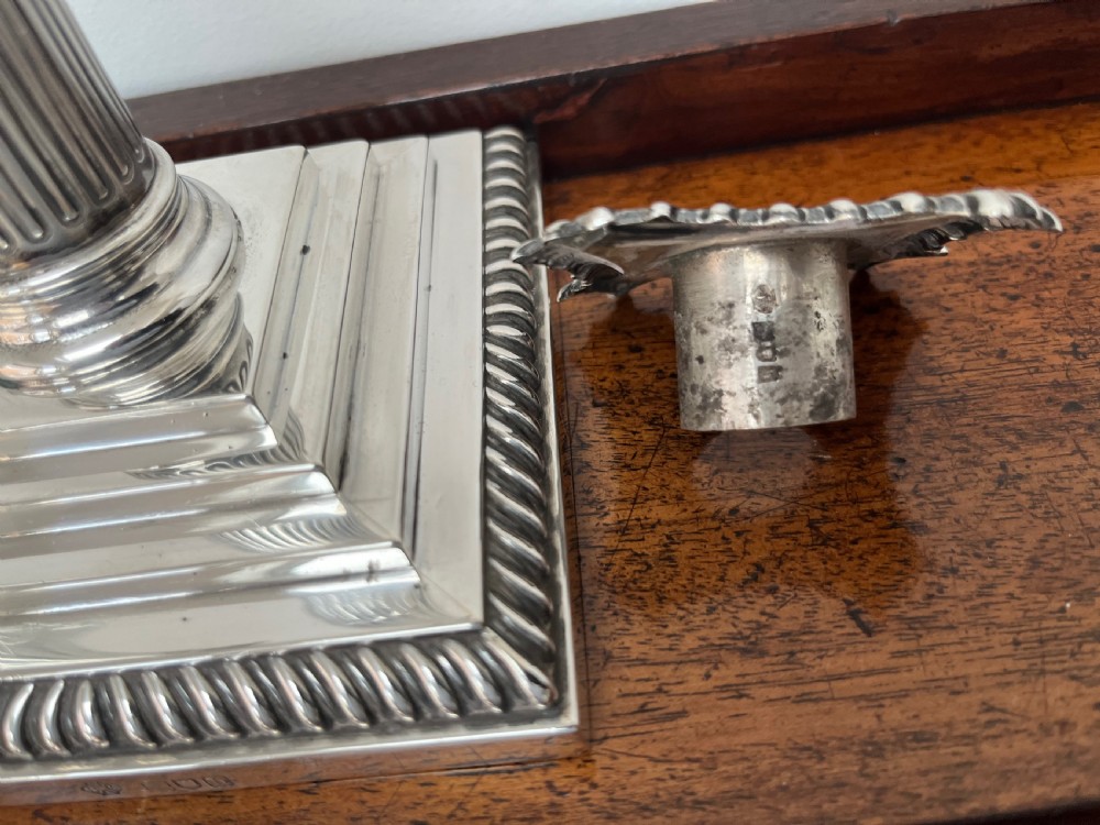 A pair of Edwardian sterling silver Corinthian column candlesticks on stepped square bases with gadrooned rims. View VIII