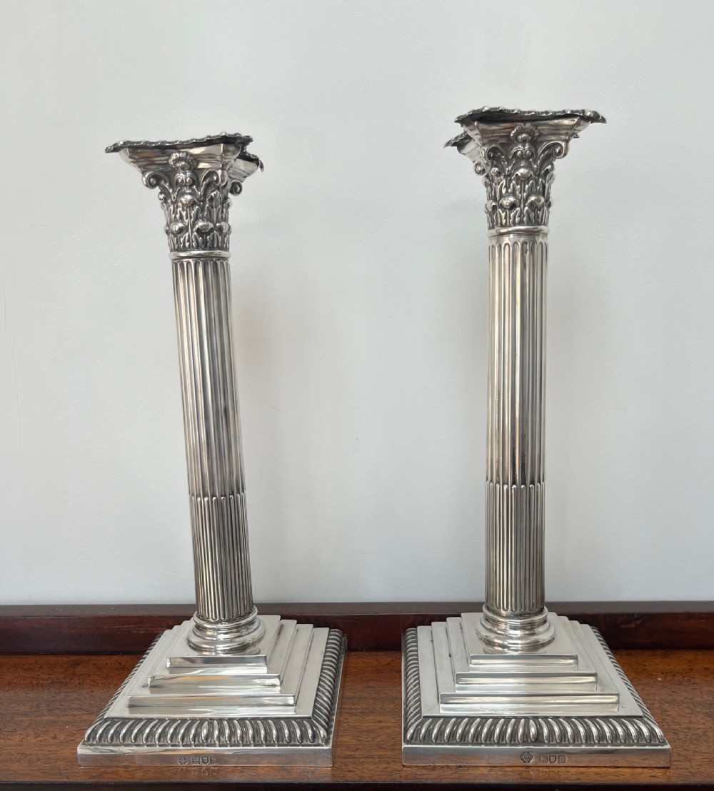 A pair of Edwardian sterling silver Corinthian column candlesticks on stepped square bases with gadrooned rims. View IX