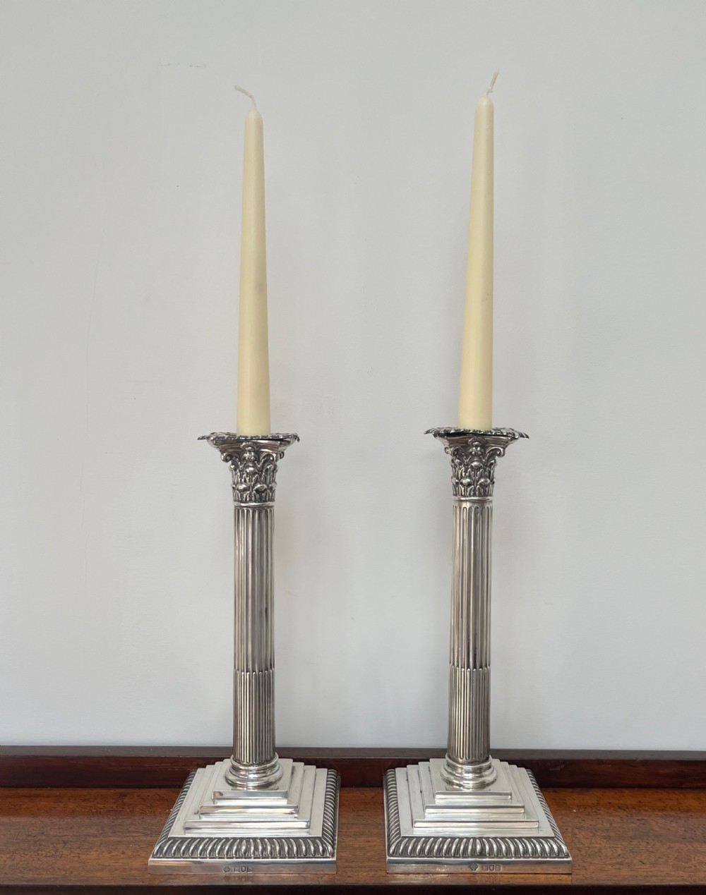 A pair of Edwardian sterling silver Corinthian column candlesticks on stepped square bases with gadrooned rims. View X