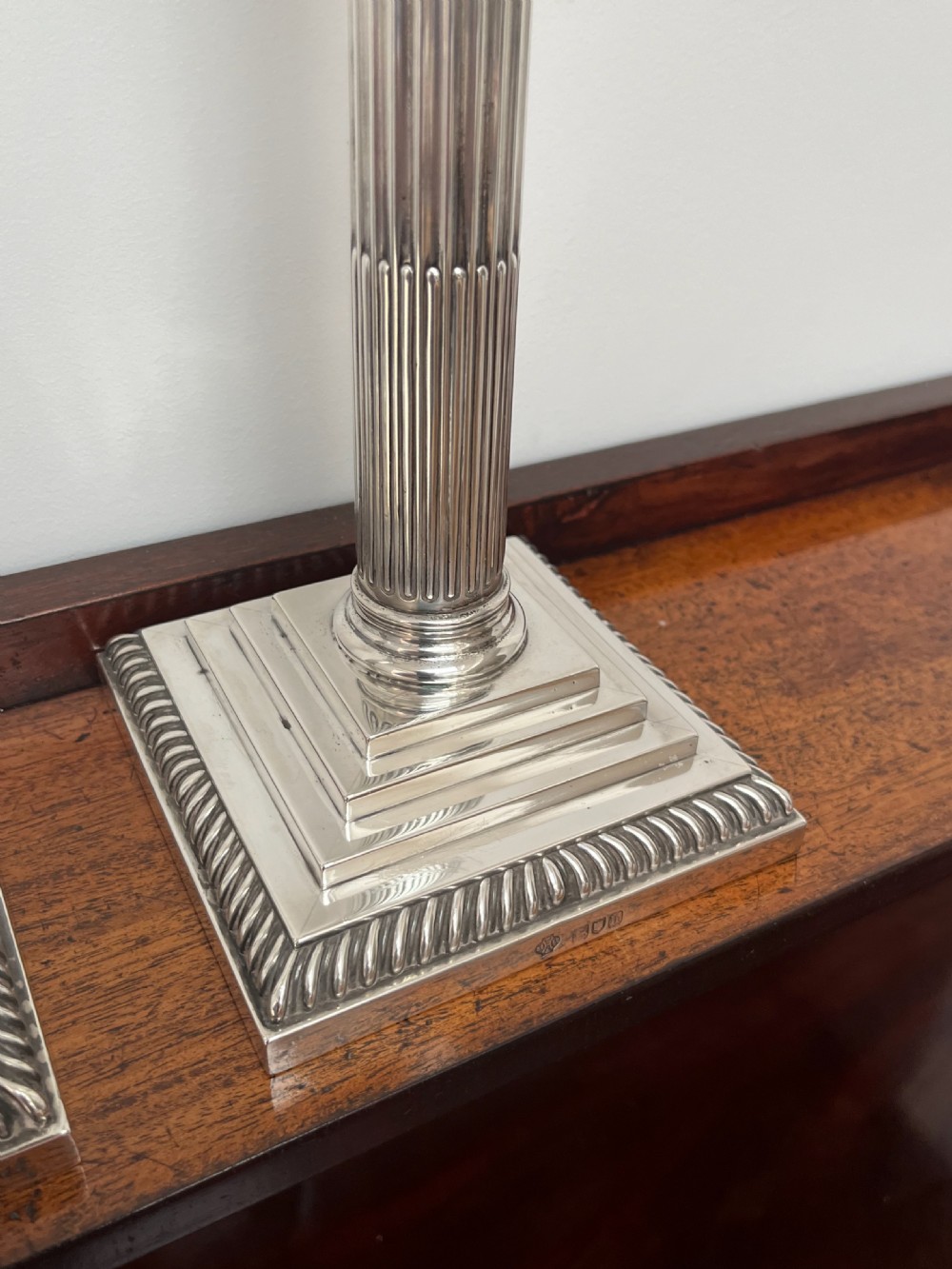 A pair of Edwardian sterling silver Corinthian column candlesticks on stepped square bases with gadrooned rims. View XIV