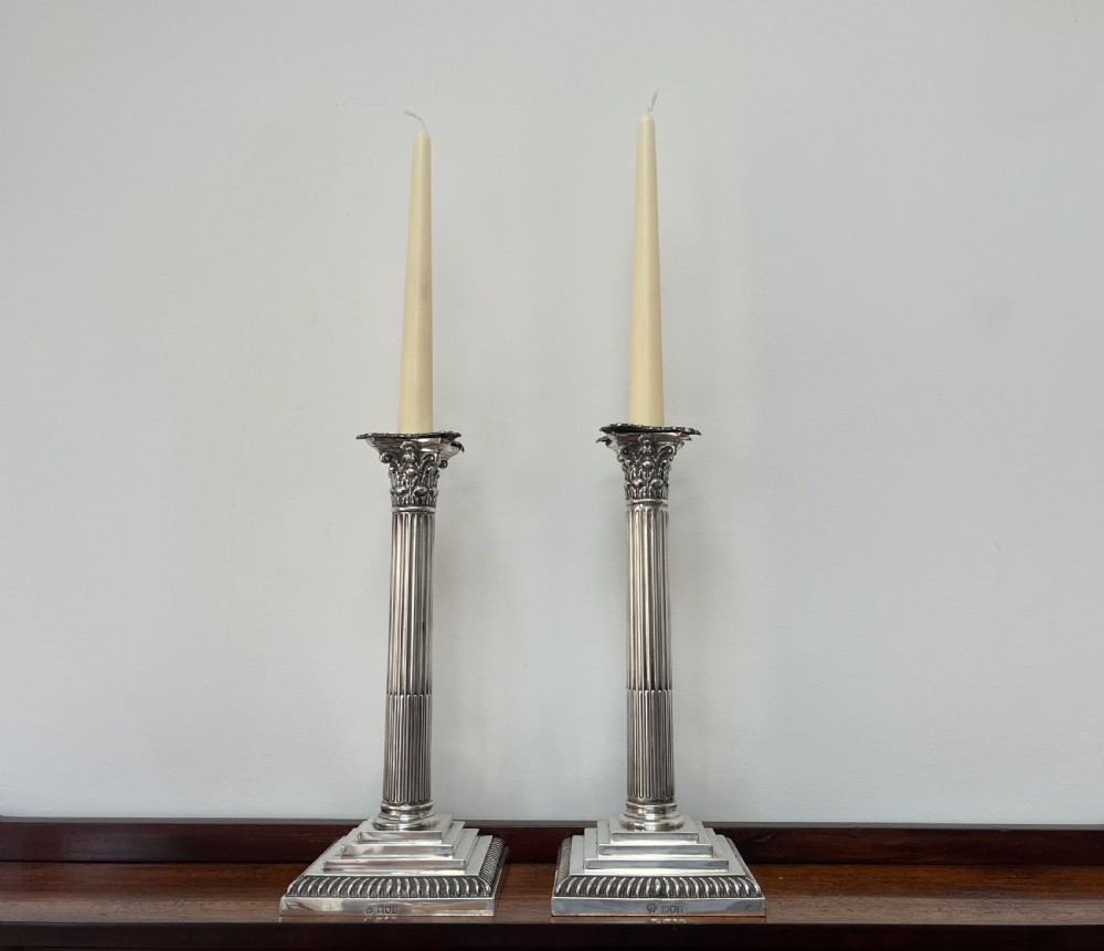 A pair of Edwardian sterling silver Corinthian column candlesticks on stepped square bases with gadrooned rims. View XV
