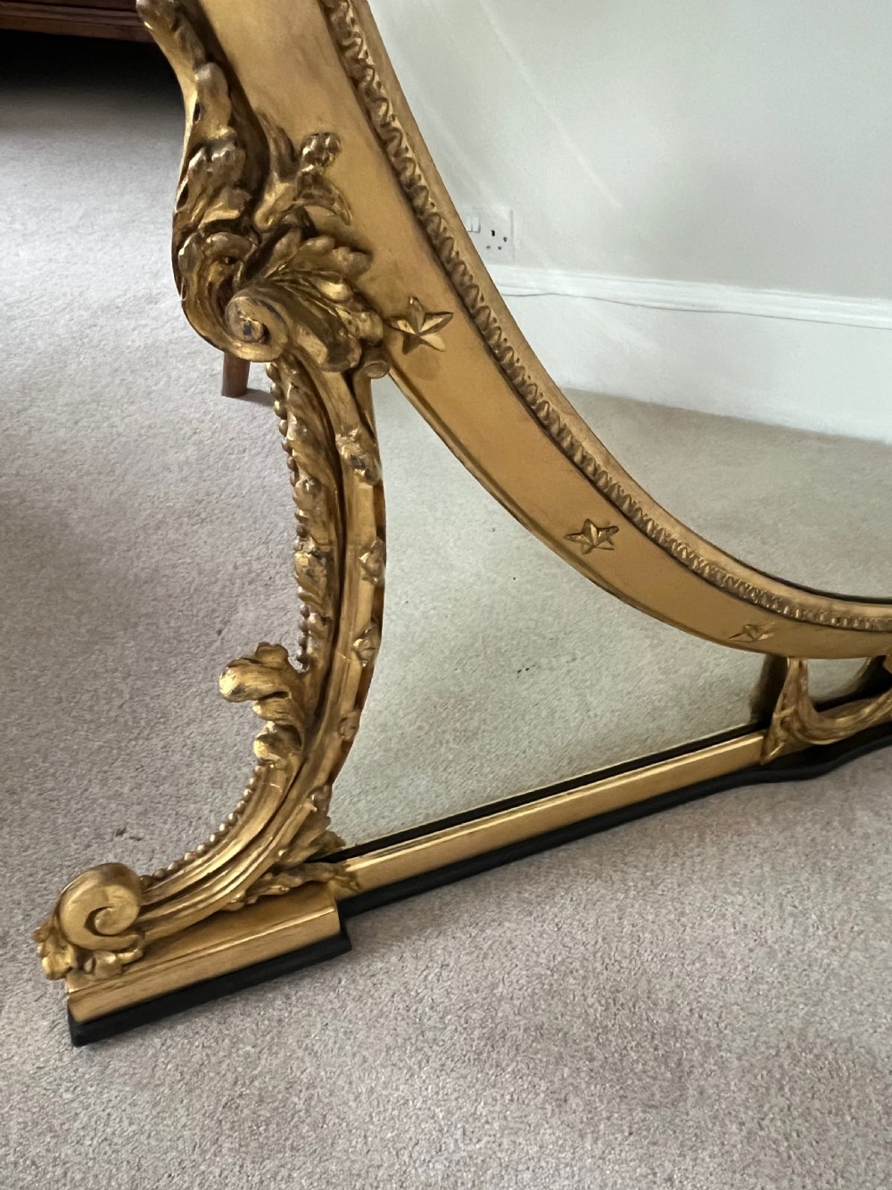 Large Victorian oval overmantel mirror featuring a gilded frame with star motifs, scrollwork base brackets, and an acanthus crest. View II
